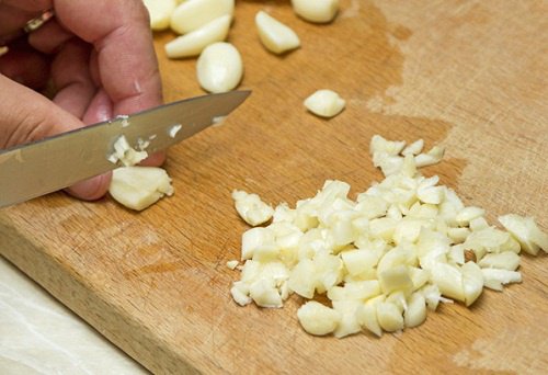 person som hackar vitlök på skärbräda