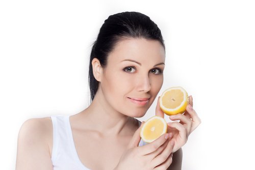 kvinna håller i en halverad citron