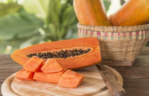 Papaya halva med kärnor och skuren papaya
