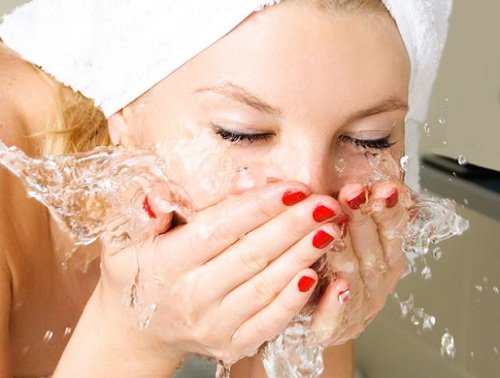 kvinna tvättar ansiktet med vatten