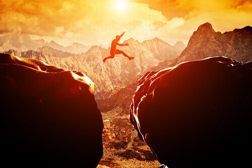 person hoppar över en klyfta i berg