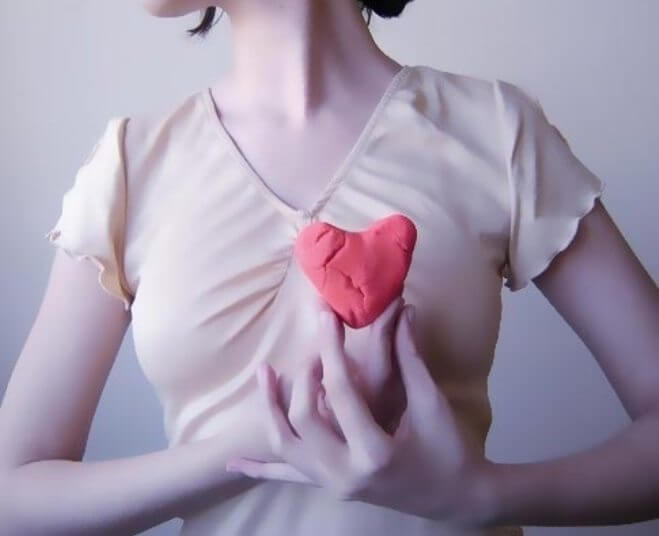 kvinna håller hjärta framför kroppen