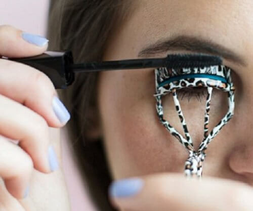 person som använder en ögonfransböjare