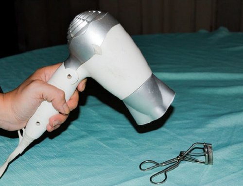 Person värmer ögonfransböjaren med hårtork