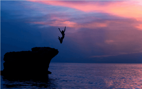 orädd kvinna hoppar från klippa i vattnet