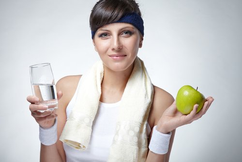 sportig kvinna med vatten och äpple i handen