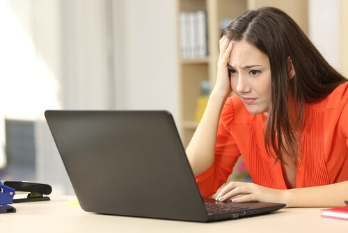 stressad kvinna framför en laptop