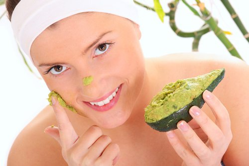 kvinna applicerar exfoliant gjord på avokado