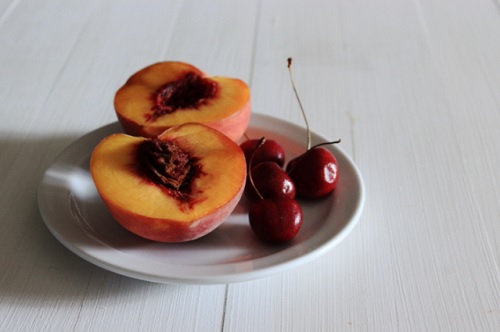 Tallrik med körsbär och persikor