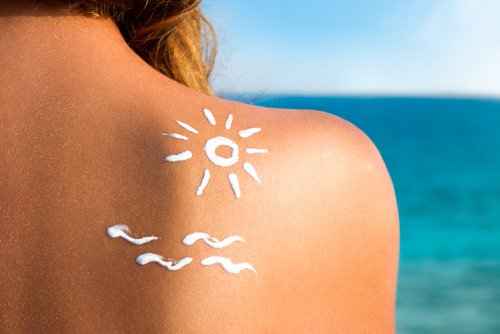 Kvinna vid hav med solkräm på rygg