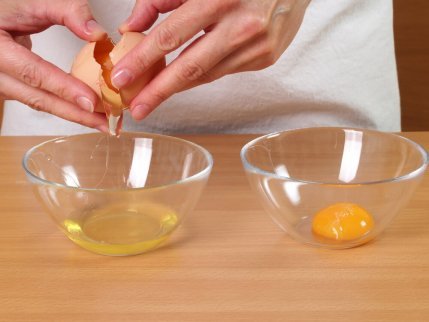 Person delar upp äggvita och äggula i skålar