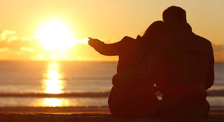 Par som njuter av solnedgången på stranden