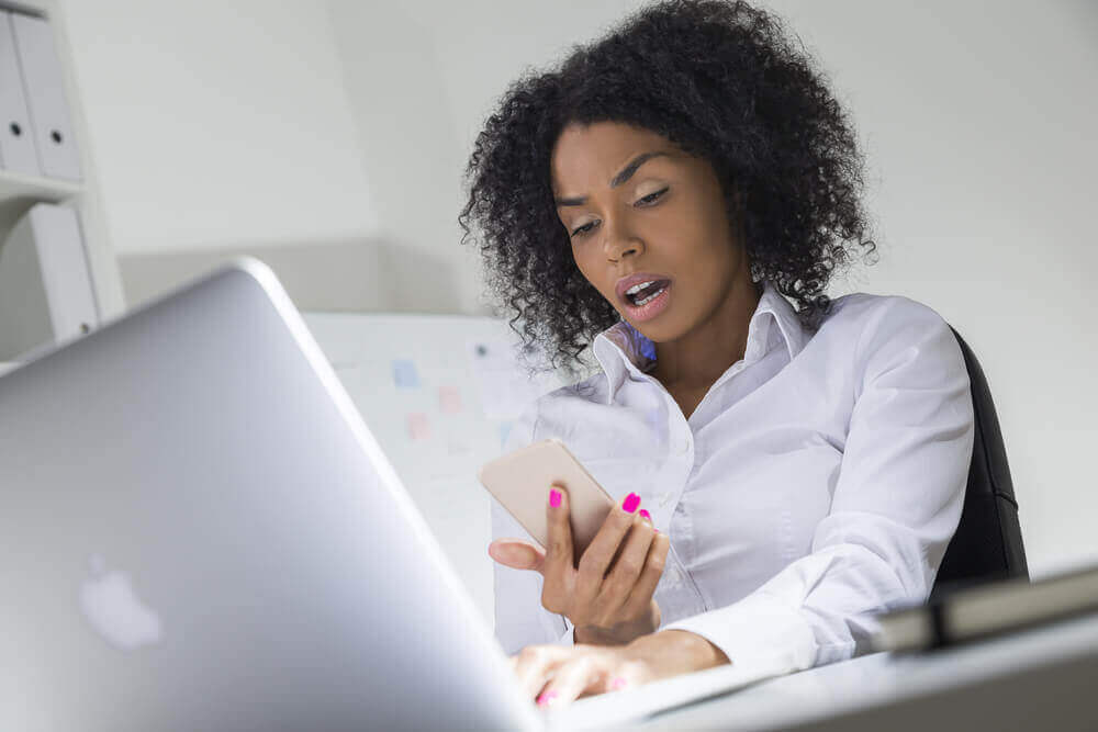 Kvinna som tittar förvånat på sin telefon.