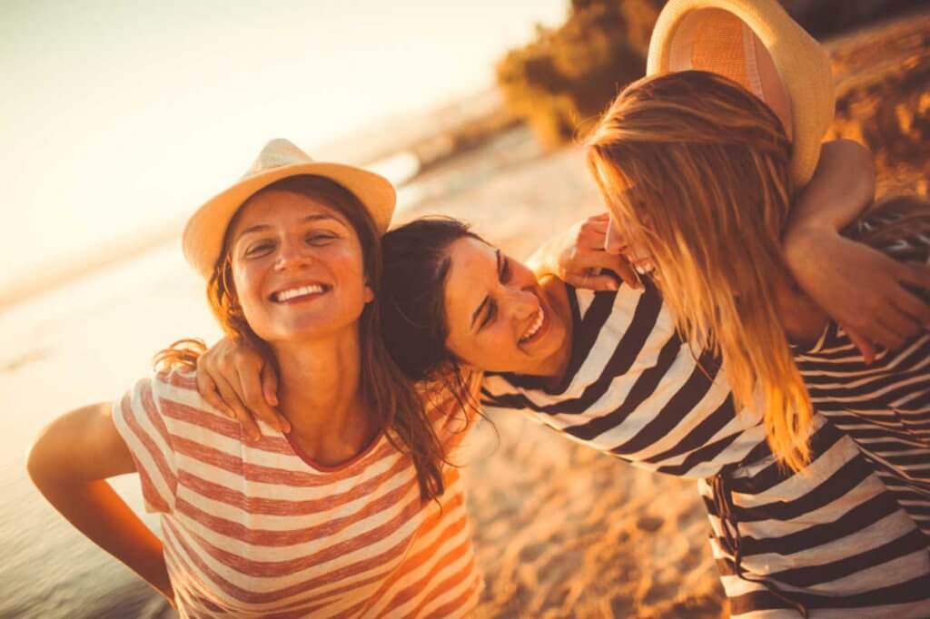 Kvinnor som skrattar på stranden.