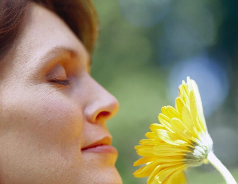 Medelålders kvinna njuter av blomma