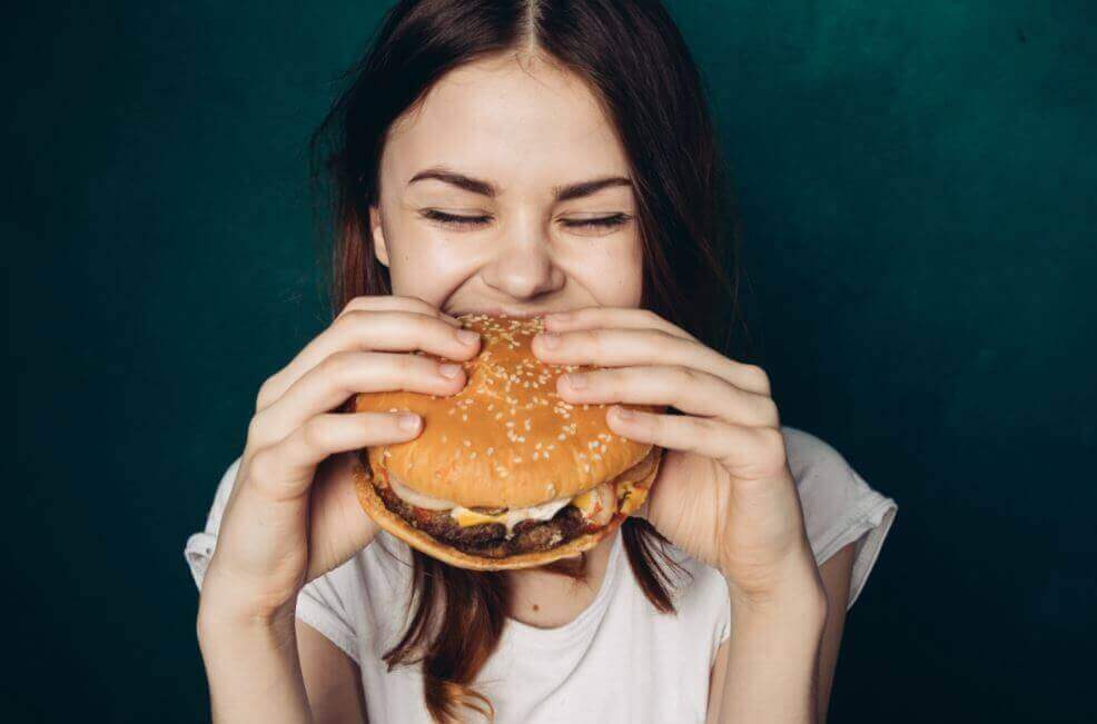 Kvinna som äter hamburgare.