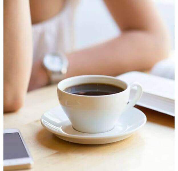 Kvinna med en kopp kaffe och sin telefon.