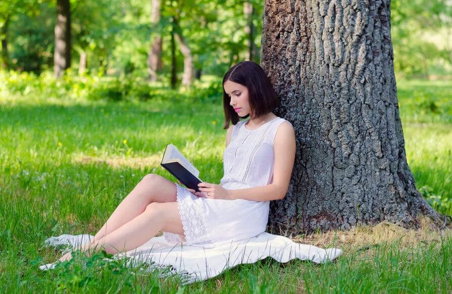 Kvinna som läser vid ett träd.