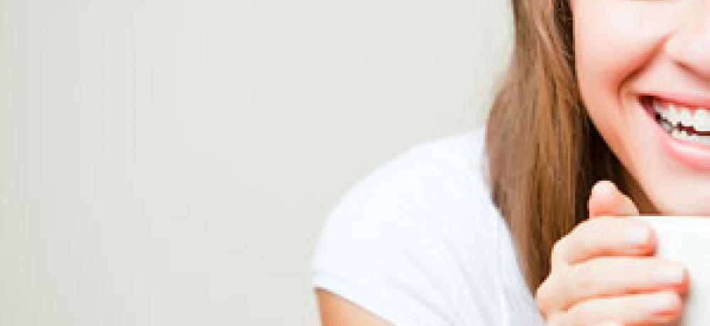 Kvinna som ser glad ut med en kopp kaffe.