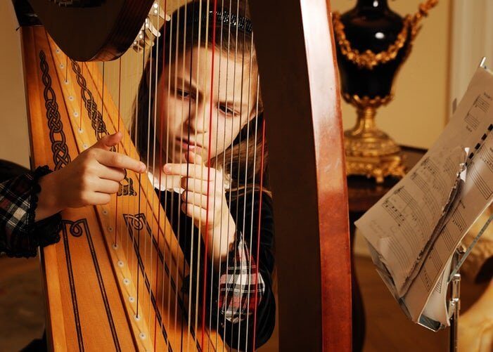 Flicka som spelar harpa.