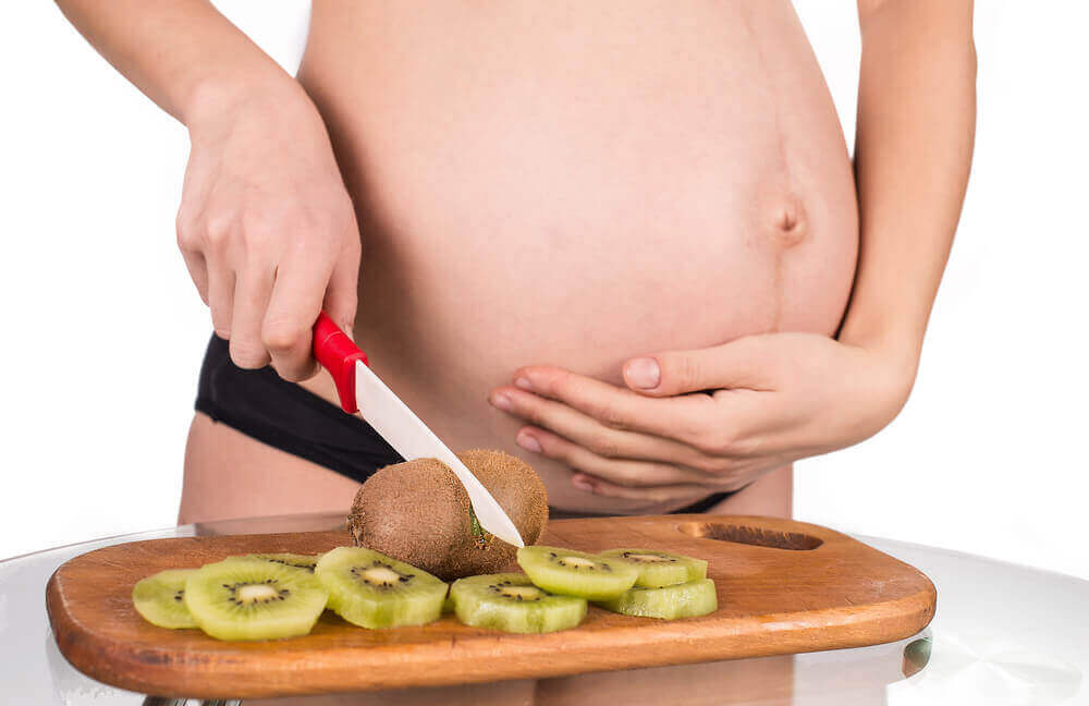 Gravid kvinna som skivar kiwi.