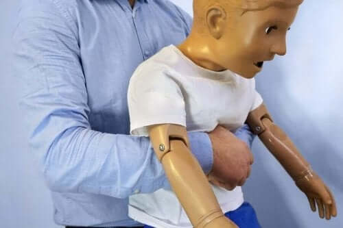Person tränar heimlichmanövern på en docka av barnstorlek.