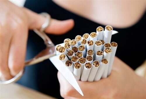 person klipper av ett paket med cigaretter