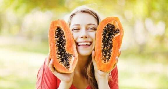 Kvinna håller upp en halvad papaya.
