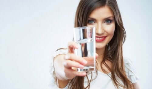 interstitiell cystit: kvinna håller upp vattenglas