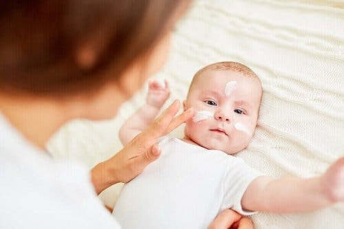 Man kan förebygga atopisk dermatit: mamma sätter kräm i ansiktet på baby