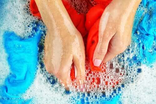 En kvinna tvättar för hand för att ta bort fettfläckar från kläder.