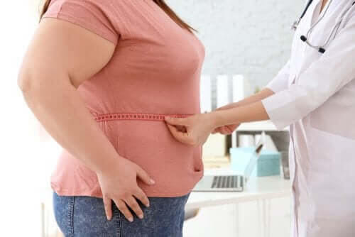 läkare mäter midjan på kvinna som ett steg i att förhindra fetma