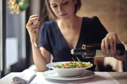 hoppa över middagen: kvinna häller olja på sallad