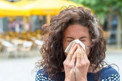 kvinna nyser i näsduk på grund av höga inomhustemperaturer