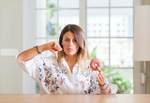 kvinna som inte tål sorbitol visar tummen ner åt frityrmunk