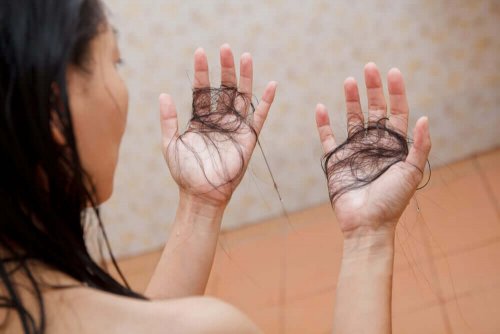 En kvinna har händerna fulla av hår efter duschen.