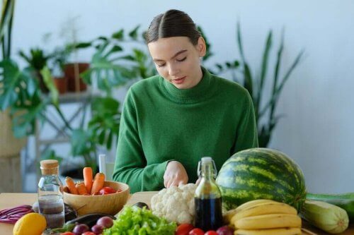 En kvinna omgiven av frukt och grönsaker fulla med A-vitamin.