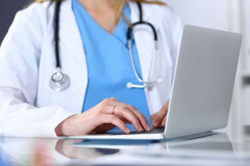 En läkare sitter framför sin dator.