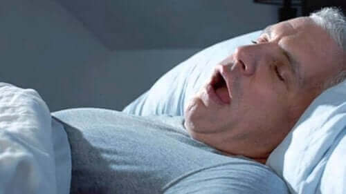 Man sover och snarkar med öppen mun.