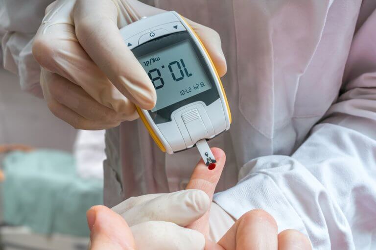 En läkare mäter patientens glukos eller blodsockerhalt.