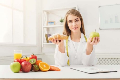 Nutritionist håller i ett äpple och en croissant.