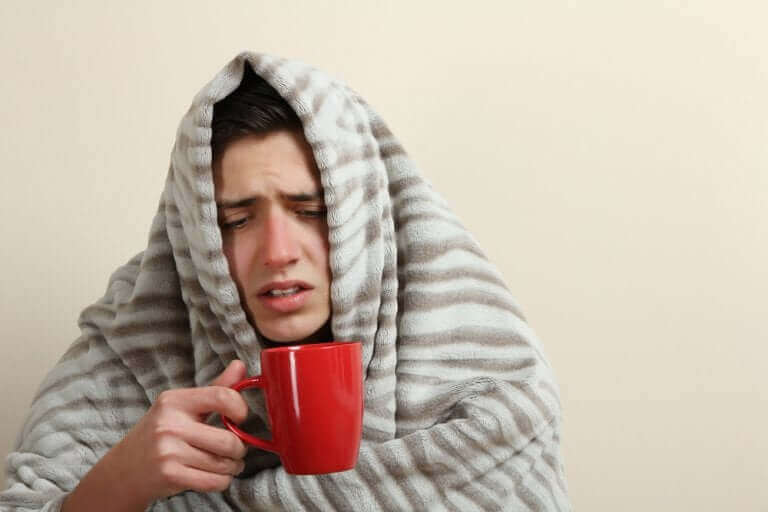 En man dricker te för att lindra symtom.