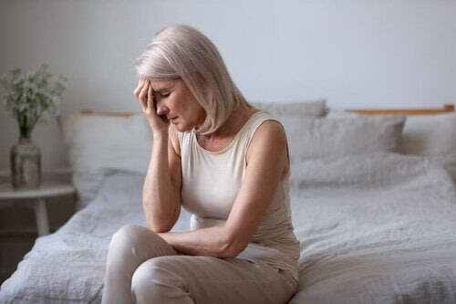 symptomen på perimenopaus: kvinna sitter på säng och ser trött ut