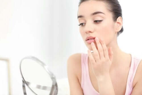 Hur behandlar man munsår: En kvinna tittar sig i spegeln.