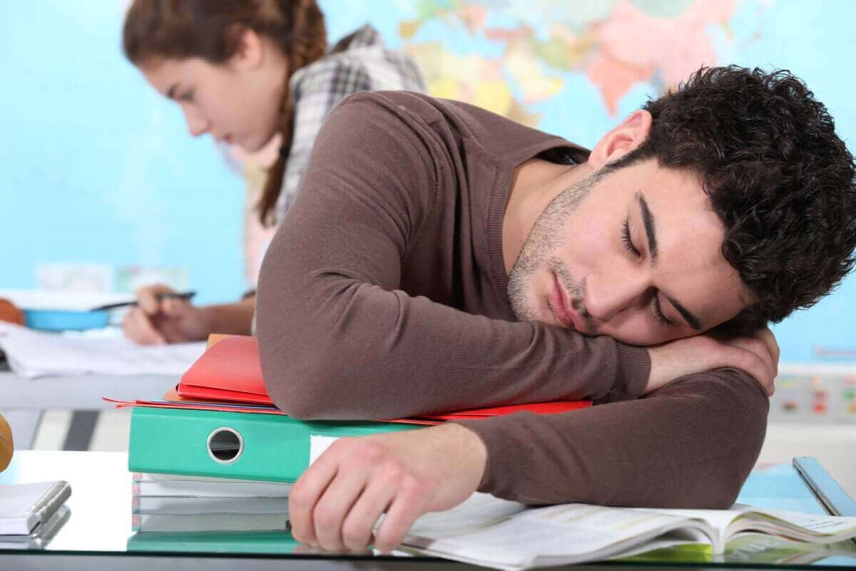 En student har somnat på sina böcker.