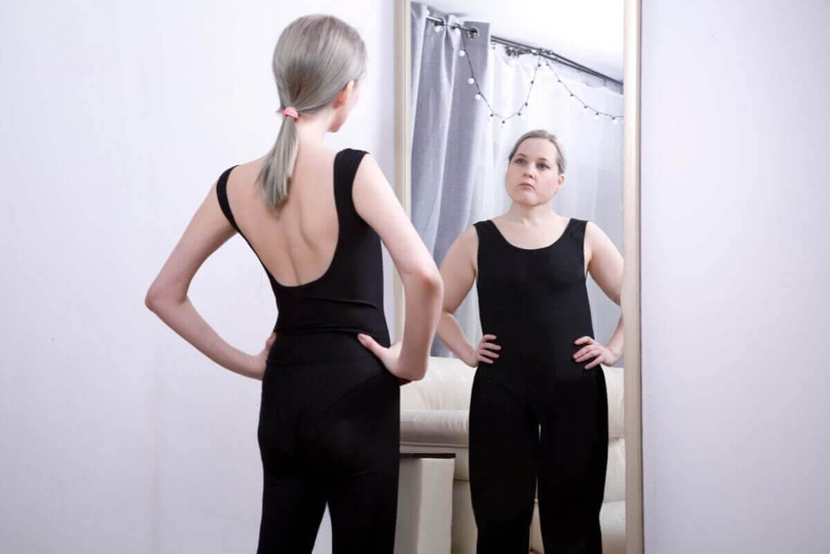 ätstörningen sadorexi: smal kvinna ser sig själv som tjock i spegel