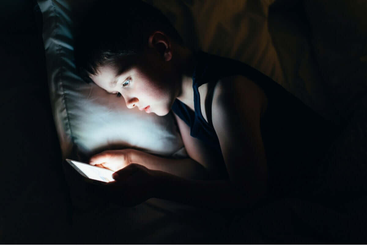 mörka ringar under ögonen: barn med skärm i säng