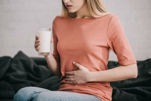 vad gör matsmältningsenzymer: kvinna håller i mjölkglas och verkar ha ont i magen