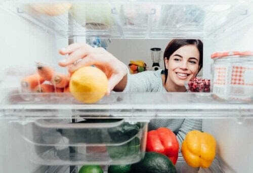 Korskontaminering från skadliga virus och bakterier: kvinna sträcker sig efter en citron i ett kylskåp