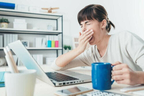 morgontrött och sömndrucken kvinna vid laptop